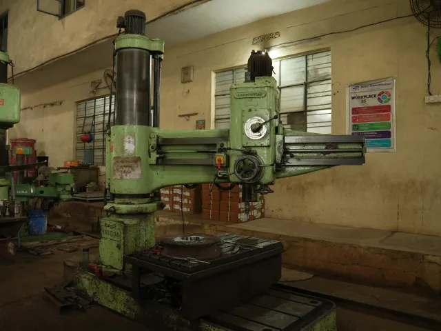 Large green drilling machine on the workshop floor.