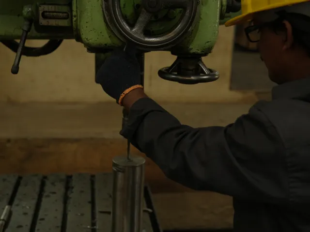 Close view of a worker operating a workshop machine.