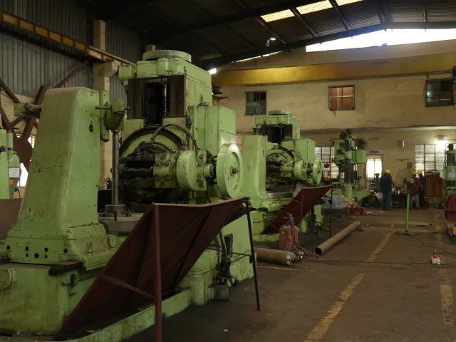 Several large green machines on the workshop floor.